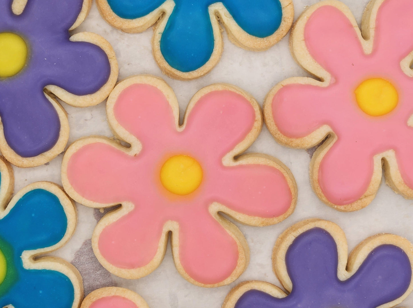 Gluten-free flower-shaped sugar cookies brightly decorated on a cookie sheet.