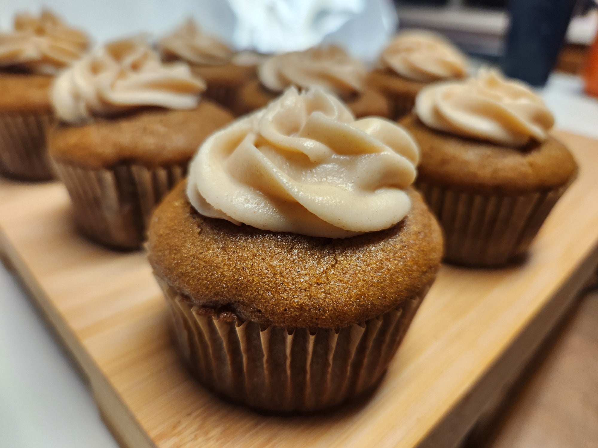 Gluten-free Pumpkin Muffins with cinnamon cream cheese frosting on a wooden board