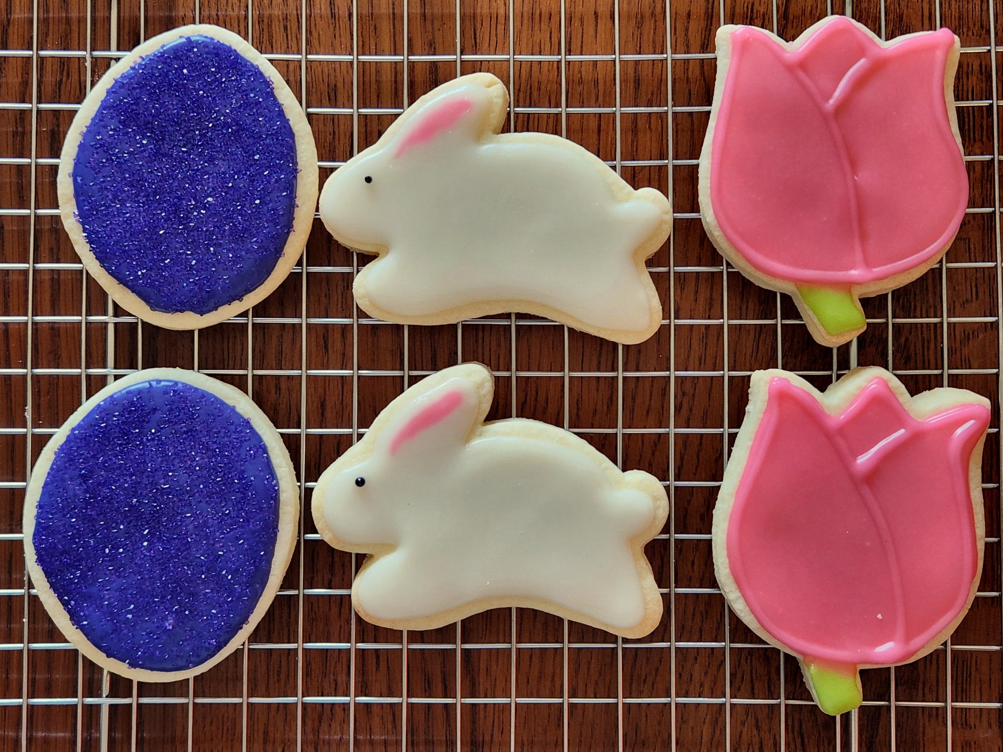 These cookies are beautifully decorated with an Easter theme! They include designs shaped like bunnies, tulips, and eggs, decorated with icing in spring colors